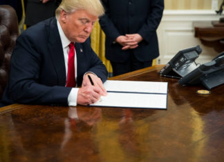 President Trump signing an executive order in the Oval Office.