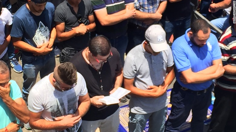 Nidal Aboud, a Christian, holds a Bible and prays beside Muslims in Jerusalem, where there recently have been clashes between Israeli forces and Palestinians.