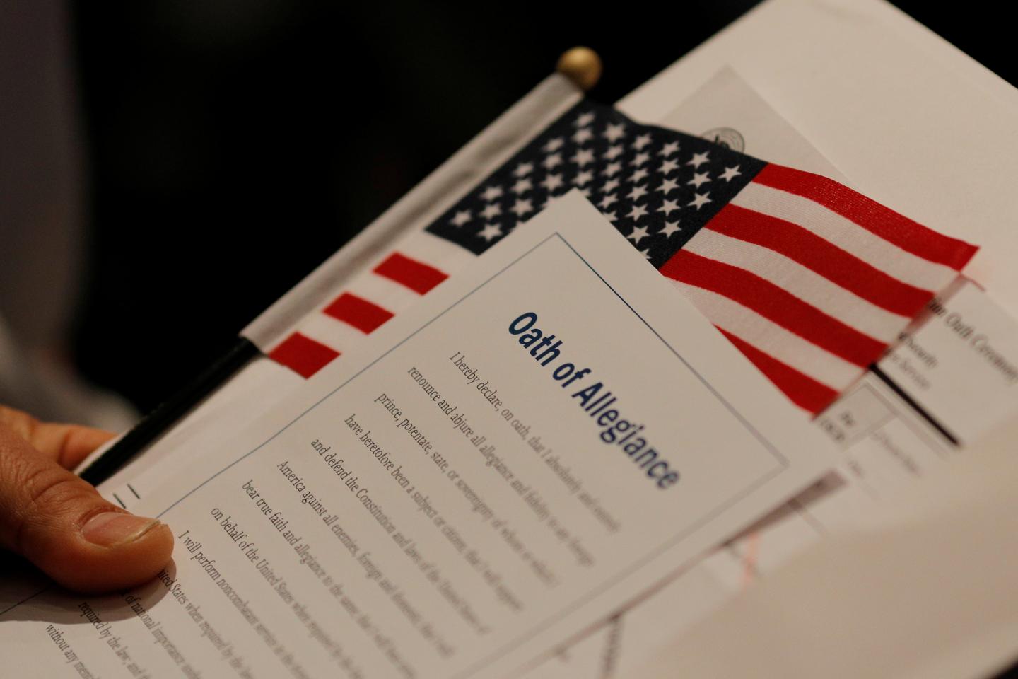 A new United States citizen holds a U.S. flag and a copy of the Oath of Allegiance during a citizenship ceremony at the John F. Kennedy Presidential Library in Boston, Massachusetts, U.S. February 8, 2017. REUTERS
