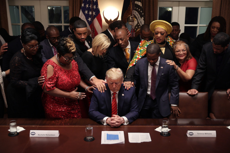 African American supporters lay their hands on U.S. President Donald Trump as they pray for him at the conclusion of a news conference and meeting in the Cabinet Room at the White House February 27, 2020 in Washington, DC.