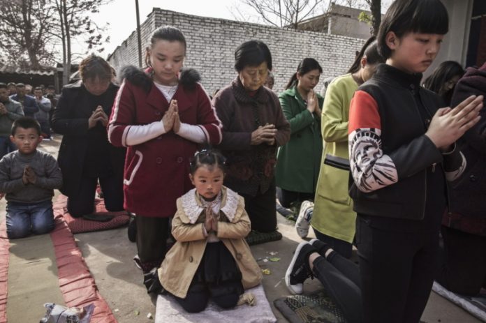 Chinese Catholic worshippers kneel and pray during Palm Sunday Mass during the Easter Holy Week at an 
